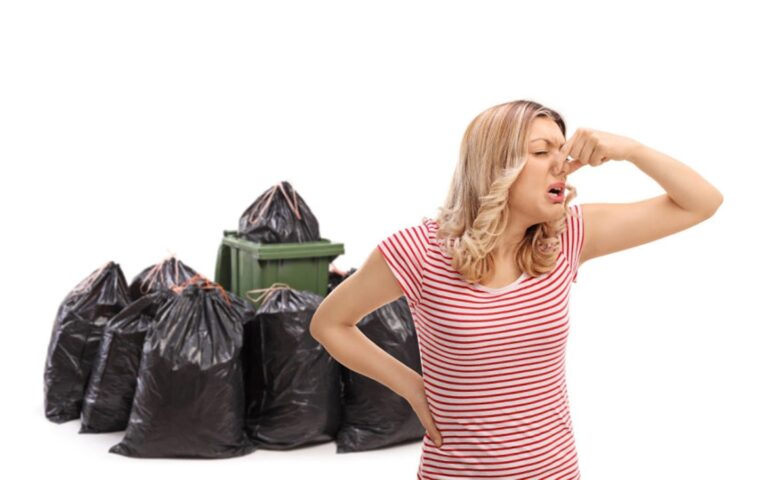 Femme qui se pince le nez en raison de l'odeur nauséabonde sortant de son bac de poubelle